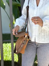 Cartera bandolera de cuero gamuzado color camel, con solapa frontal y cierre principal. Incluye dos correas desmontables, una corta y una larga regulable, y cuenta con bolsillo interior.