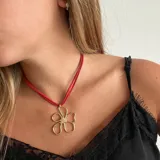 Collar con doble tira de gamuza roja y dije de flor dorada con centro de pedrería.