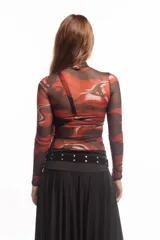 Top de cuello alto y manga larga confeccionado en tejido de malla semitransparente con estampado artístico abstracto en tonos rojizos, negros y blancos.