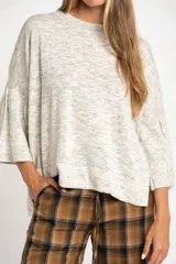 Sweater de punto con efecto jaspeado, de corte oversize, cuello redondo y mangas largas con terminación acampanada tipo volado.