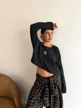 Remera de manga larga color marrón, con cuello redondo y detalle de parche cuadrado con logo bordado en el centro del pecho. Presenta un corte holgado y diseño minimalista.