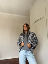 Campera puffer con estampado de leopardo en tonos blanco y negro, cuello alto, cierre frontal y bolsillos laterales.