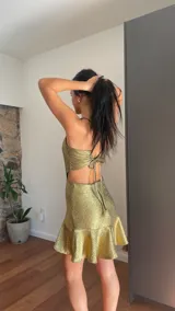 Vestido corto dorado de lamé elastizado, con escote corazón, breteles finos y falda con volados.