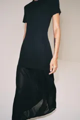 Vestido largo negro de punto con cuello redondo, manga corta y bajo con tejido combinado semitransparente.