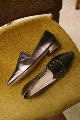 Chatitas negras de cuero con punta fina y apliques de tachas doradas.