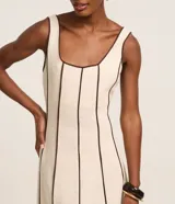 Vestido largo evasê sin mangas de color beige, con escote cuadrado y costuras verticales con bies en tono contrastante oscuro.