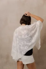 Kimono marfil de silueta amplia, confeccionado en tela con bordados florales y detalles calados. Cuenta con mangas amplias tres cuartos, frente abierto y terminaciones decorativas.