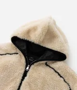 Campera de fleece color beige con diseño de paneles, costuras expuestas en color negro y cierre frontal. Posee cuello alto, mangas largas con puños elásticos y forro interior.