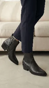 Bota corta tipo chelsea de cuero negro, con panel lateral texturizado y taco cuadrado bajo.
