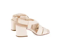 Sandalias de tacón medio color blanco hueso, con tiras cruzadas acolchadas en la parte delantera y talonera elástica fruncida. Tienen punta cuadrada y tacón ancho de 6 cm.