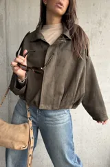 Campera tipo bomber de gamuza color verde, con diseño oversize, cuello camisero, cierre frontal y detalles de charreteras en los hombros.