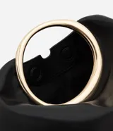 Cartera de mano Satinato tipo clutch, confeccionada en poliuretano color negro. Presenta un diseño moderno con una asa rígida metálica en formato ovalado y cuerpo estructurado.