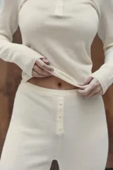 Pantalón negro de tejido de punto, tiro alto, con cintura elástica y detalle de tres botones frontales. Corte de pierna recta y ancho.