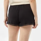 Pantalón corto de pijama negro, de tela fluida, con cintura elástica ajustable con cordón y detalle de bordado de encaje en el dobladillo.