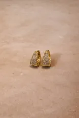 Aros tipo argolla con base metálica dorada e incrustaciones de cristales negros en toda su superficie frontal.