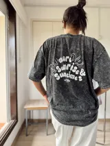 Remera gris con efecto lavado y estampado de trébol con texto en el frente. Corte holgado y mangas cortas.