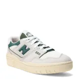 Championes New Balance modelo 550, color blanco hueso con detalles en verde oscuro. Presentan un diseño de corte bajo inspirado en el básquet, con paneles de cuero y malla, y el logo 'N' en verde oscuro. La suela es de goma color crema.