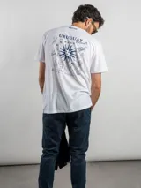 Remera blanca de corte regular con estampado gráfico en la espalda que incluye elementos icónicos de la cultura uruguaya como el sol, un tambor, una parrilla y frases alusivas. Cuenta con cuello redondo y mangas cortas.