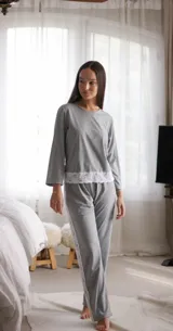 Pijama de algodón gris con textura acanalada, compuesto por una remera de manga larga con detalle de puntilla blanca en el ruedo y un pantalón recto a juego con franja lateral de puntilla blanca.
