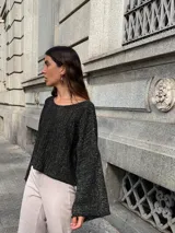 Buzo de punto color beige claro, con tejido acanalado y escote en V. Presenta mangas amplias y corte holgado.