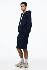 Short de felpa interlock color negro, de corte relajado a la rodilla, con cintura elástica con cordón ajustable oculto y bolsillos laterales.