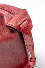 Bolso de hombro de cuero con textura granulada, diseño estructurado y cierre superior con tirador de cuero. Cuenta con una correa ajustable y detalles de costuras reforzadas en la base.