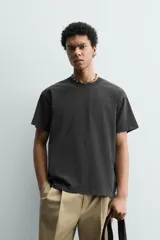 Camiseta de corte boxy fit, con cuello redondo y manga corta. Presenta un acabado irregular con efecto lavado que le otorga un aspecto vintage.