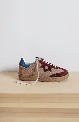 Zapatillas bajas de cuero color beige con detalles en marrón y azul. Cordones blancos y suela de goma color caramelo.