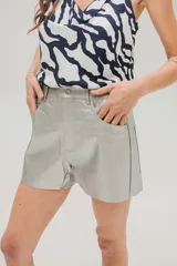 Short de tiro medio confeccionado en cuerina con acabado metalizado plateado. Presenta cierre frontal con botón metálico, bolsillos laterales y diseño de corte recto.