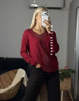 Sweater de punto color bordó con escote en V y detalle de strass aplicado en la parte frontal. Presenta mangas largas y corte holgado.