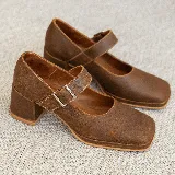 Zapato estilo Mary Jane de cuero vacuno con acabado brillante, punta cuadrada y taco bloque. Cuenta con una tira ajustable sobre el empeine con hebilla metálica.