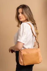 Bandolera de diseño práctico con combinación de texturas en tonos tierra, confeccionada en tela y símil cuero. Cuenta con un compartimento principal con cierre, un bolsillo frontal con cierre y correa ajustable para llevar al hombro o cruzada.