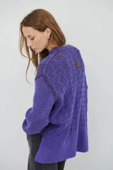 Buzo reversible de tejido de punto con diseño de trenzas, cuello redondo y mangas largas. Presenta una combinación de colores en contraste, con un lado en violeta y el otro en marrón oscuro.