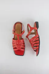 Sandalias de cuero color negro, de suela plana, con tiras entrelazadas en la capellada y tira ajustable en el talón con hebilla metálica.