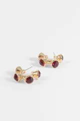 Aros tipo argolla pequeña de metal dorado con diseño geométrico y aplicaciones de piedras rojas facetadas.