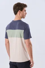 Remera de manga corta con diseño de bloques de color en tonos gris, blanco y azul marino. Cuenta con cuello redondo y una estampa tipográfica en el centro del pecho.