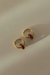 Par de aros tipo argolla dorados de acero quirúrgico, con una piedra natural de color gris translúcido colgando de cada uno.