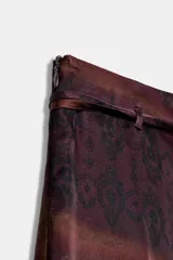 Falda midi de tiro medio, con estampado paisley en tonos bordó y dorado, y detalle de cinturón confeccionado en el mismo tejido.