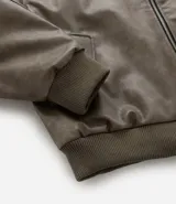 Campera bomber de poliuretano con acabado efecto cuero, cuello redondo, cierre frontal con cremallera, bolsillos delanteros y bolsillo utilitario en la manga. Presenta puños y ruedo elásticos, con forro interior en contraste.