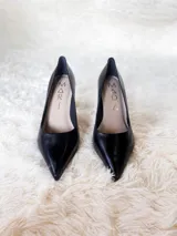 Zapatos de tacón alto con textura de reptil, color negro, con suela roja característica.