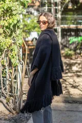 Ruana tejida a mano en punto arroz, color negro, con detalle de flecos en los bordes.