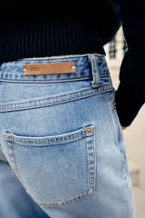 Jeans de tiro medio y corte relaxed fit, color azul con efecto deslavado, diseño de cinco bolsillos y bajo vuelto. Cuenta con cierre frontal de cremallera y botón metálico.