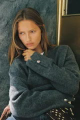 Jersey de punto suave con cuello en V y manga larga, con detalle de botones metálicos en los puños.