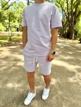 Conjunto deportivo compuesto por una remera de manga corta y un short lila con cordón de ajuste blanco.