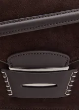 Bolso de hombro tipo baguette confeccionado en piel de serraje color marrón oscuro. Presenta un diseño rectangular con cierre de solapa y detalle metálico frontal. Incluye forro interior y bolsillo interno.