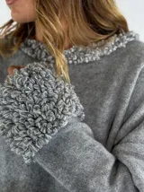 Sweater gris de manga larga con cuello redondo y puños con detalle de volados de lana rizada.