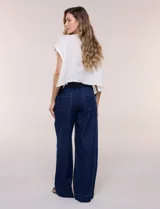 Jean de tiro alto y pierna amplia de corte wide leg, confeccionado en denim azul. Presenta cintura plana en el frente y elastizada en la espalda, bolsillos delanteros aplicados estilo parche y pespuntes a contrapunto.