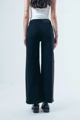 Jean de corte wide leg y tiro alto, color negro, con paneles laterales en el ruedo que aportan mayor amplitud y movimiento.