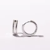 Par de aros tipo argolla plateados con diseño trenzado y pequeños brillantes incrustados.