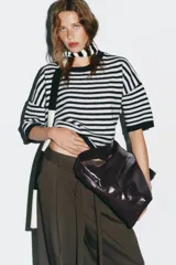 Bolso maxi shopper color marrón oscuro, con asa ancha ajustable con hebilla. Incluye bolsillo interno con cierre de cremallera metálica y cierre imantado.